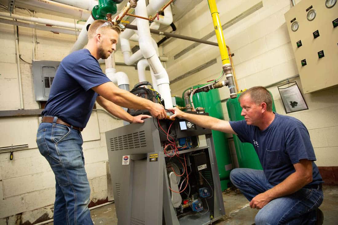 Two HVAC technicians performing a furnace replacement service
